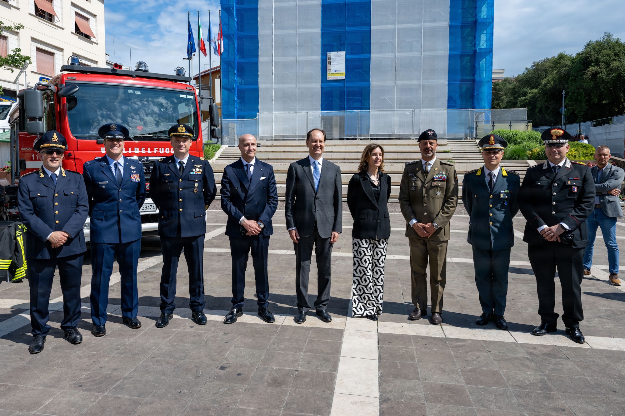 Men in military uniform and government officials stand together for a photo