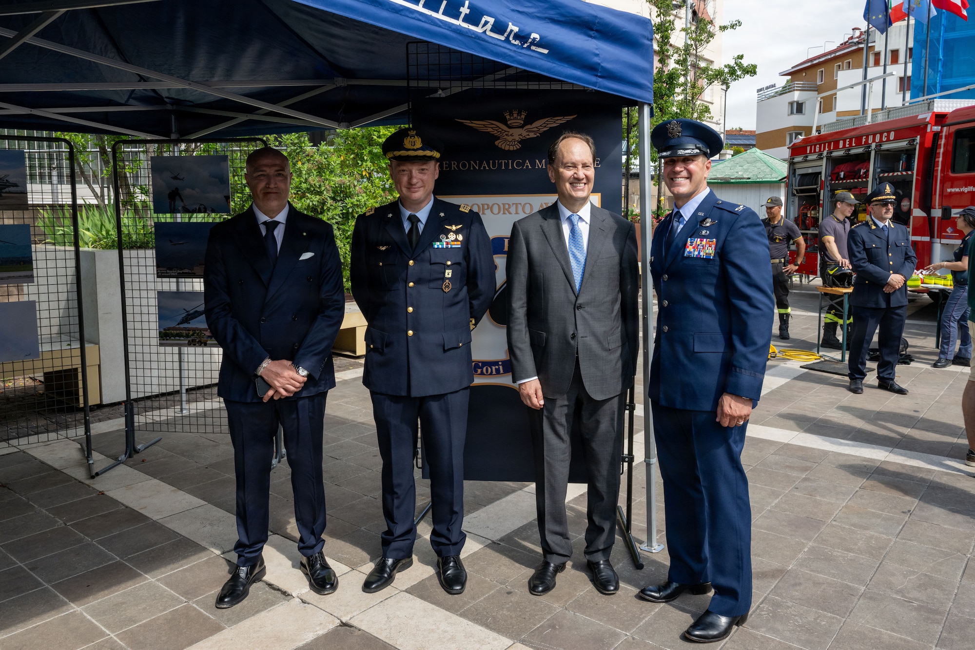 Men in military uniforms and suits stand together for a photo