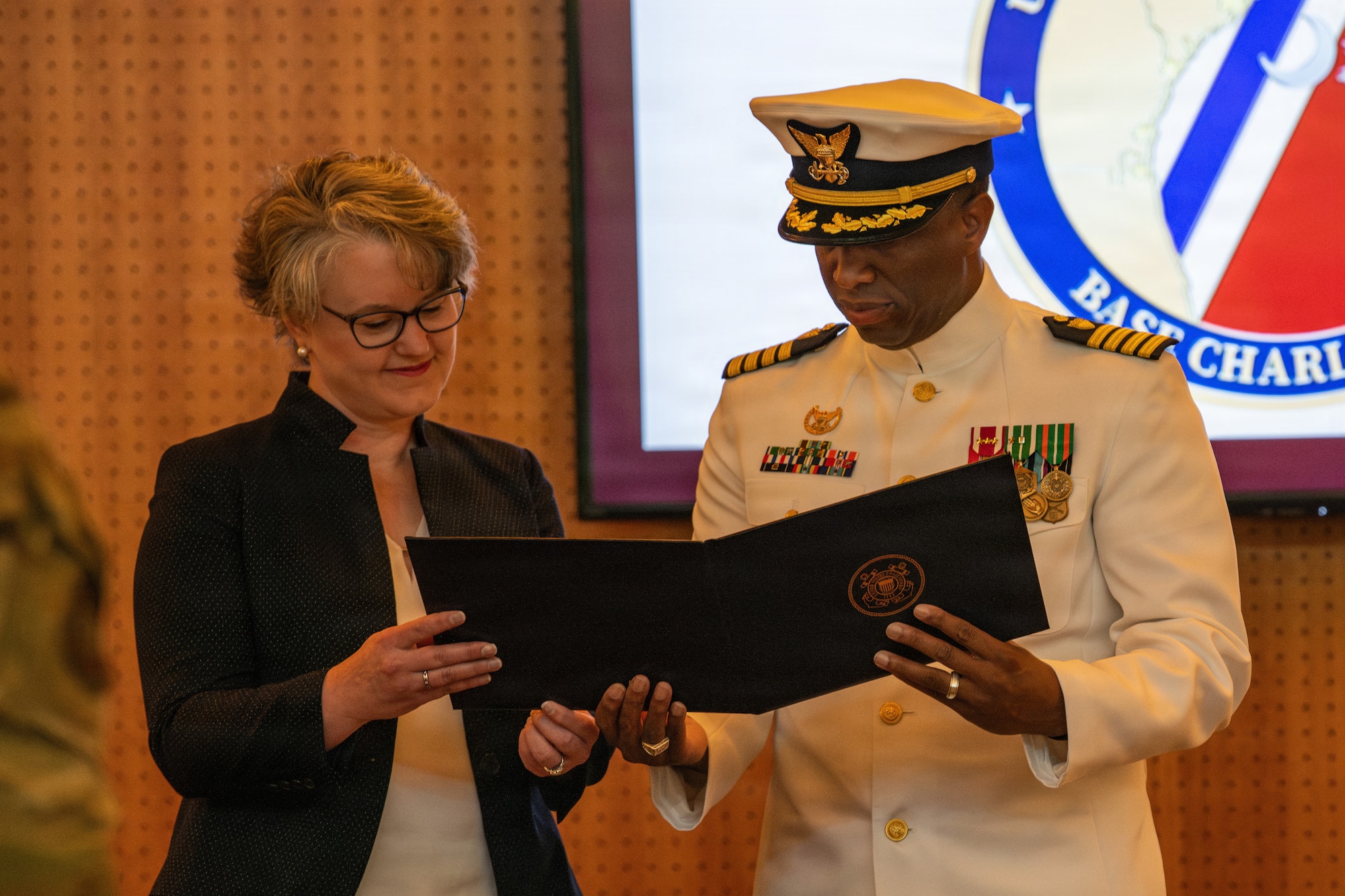 U.S. Coast Guard outgoing commander and director of Operational Logistics Command reading over a certificate.