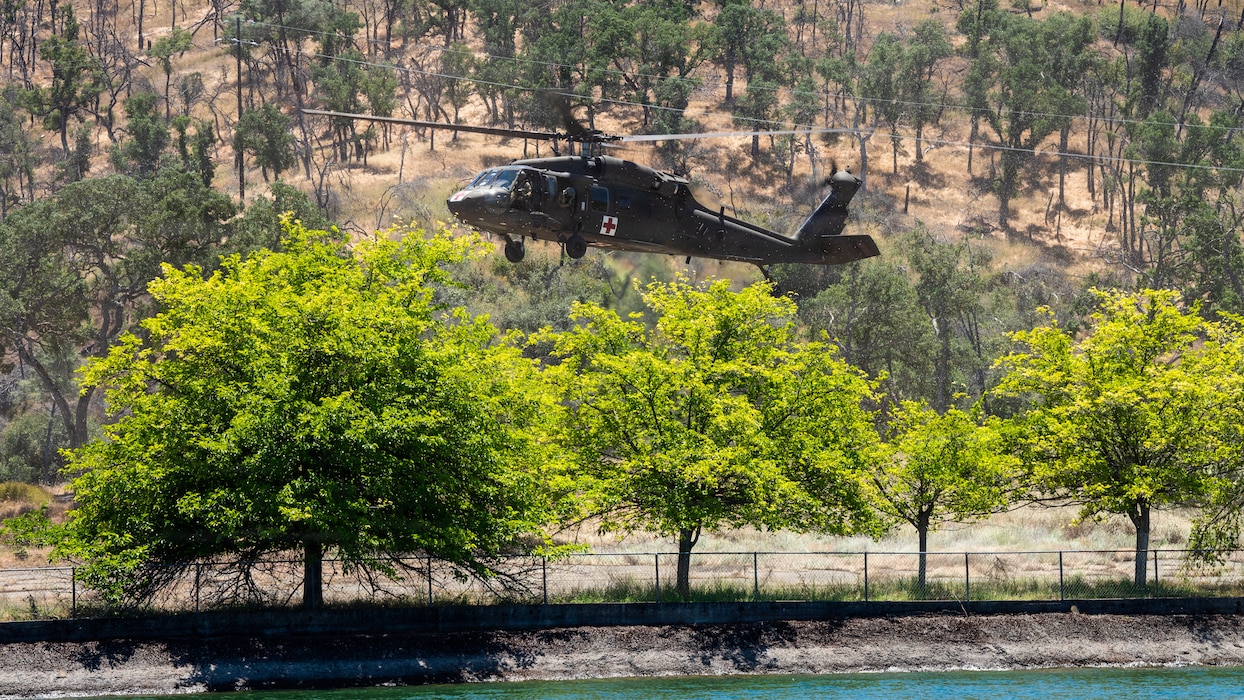 Helicopter hovers to lands and drop off Airmen