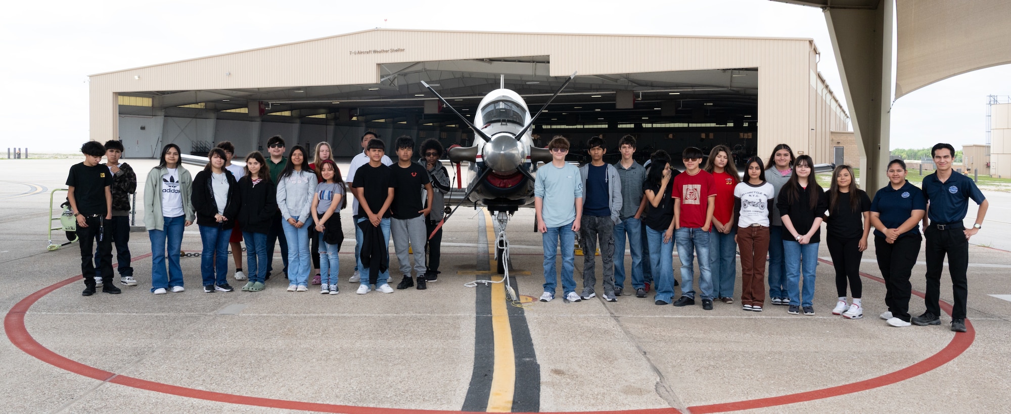 Students from the UT Austin Gaining Early Awareness and Readiness for Undergraduate Program (GEAR UP) pose for a photo in front of a T-6A Texan II at the T-6 Weather Shelter at Laughlin Air Force Base, Texas, May 5, 2026. The GEAR UP program is a U.S. Department of Education-funded college and post-secondary career access and awareness initiative that helps low-income and historically underrepresented students prepare for and succeed in higher education. (U.S. Air Force photo by Joseph Pagan)