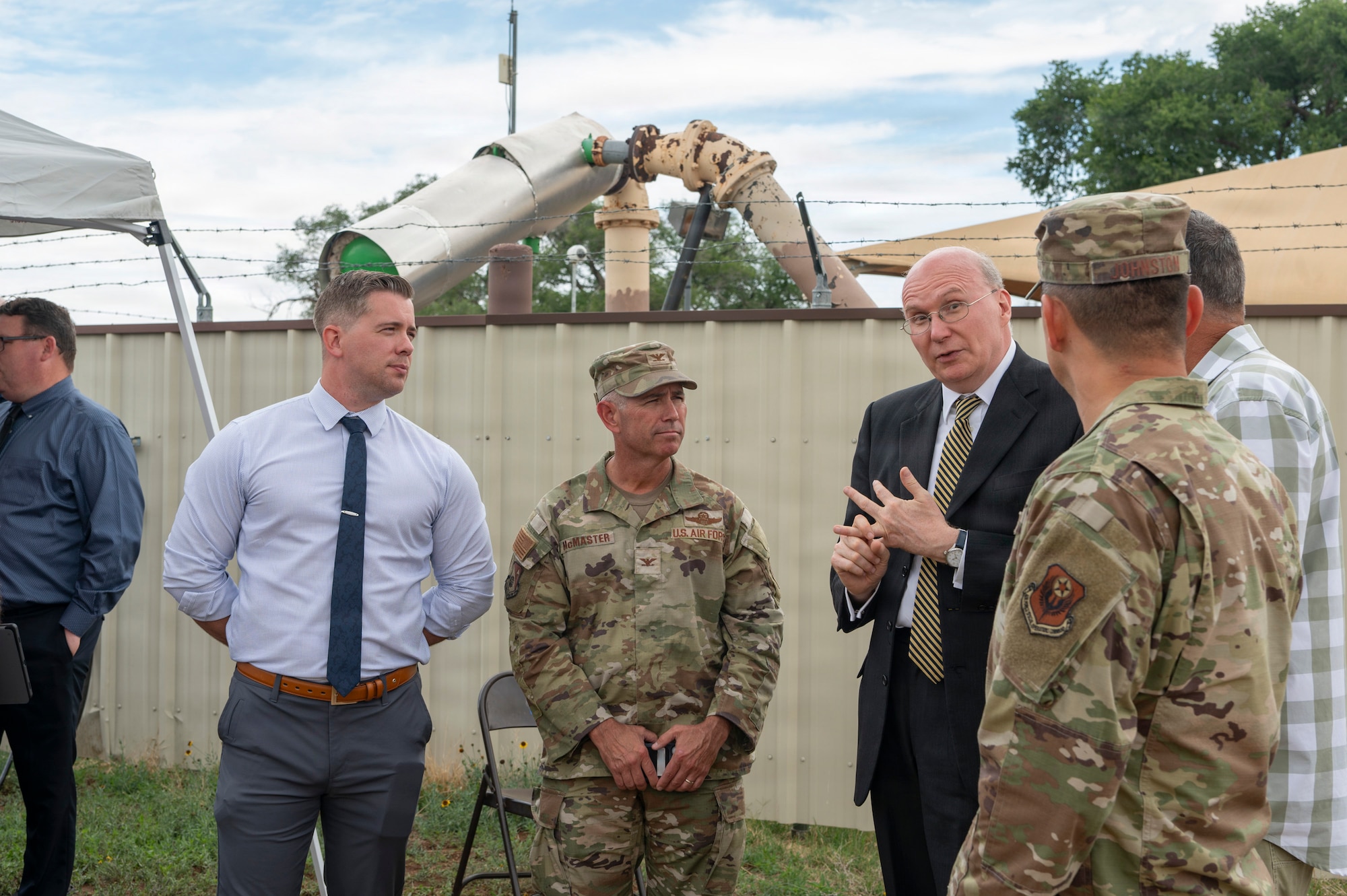 a group of people in suits and uniforms stand in a group talking
