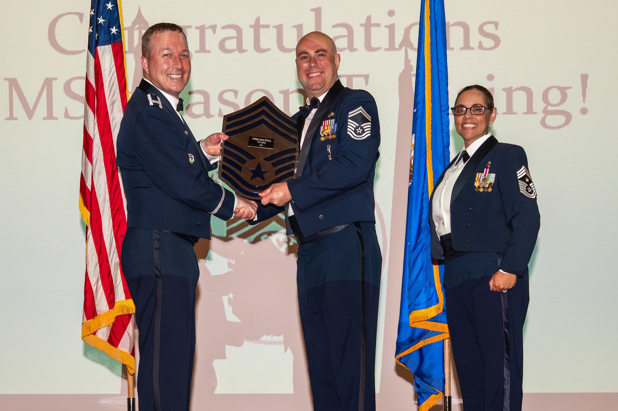 U.S. Air Force Senior Master Sgt. Jason Elsing, 741st Maintenance Squadron senior enlisted leader, center, receives a plaque from Col. Daniel Voorhies, 341st Missile Wing commander, in recognition of his advancement to the pinnacle of the enlisted rank structure, during the 2026 Chief Master Sgt. recognition ceremony at Malmstrom Air Force Base, Montana, May 29, 2026.