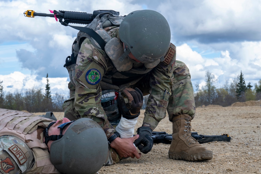Airman 1st Class Jon-Charles Tevis, 354th CES pavement and equipment apprentice, right, gives Senior Airman Nolan Butch, 354th Civil Engineer Squadron heavy equipment, Tactical Combat Casualty Care aid during an Agile Moose drill at Eielson Air Force Base, Alaska, May 28, 2026.