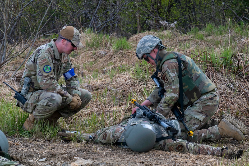 2nd Lt. Jack Flynn, 354th Civil Engineer Squadron requirements and optimization officer in charge, left, watches as Airman 1st Class Jimarion Belizaire, 354th CES power production apprentice, receives Tactical Combat Casualty Care aid from Airman 1st Class Riley Gootrad, 354th CES structural apprentice during an Agile Moose drill at Eielson Air Force Base, Alaska, May 28, 2026.