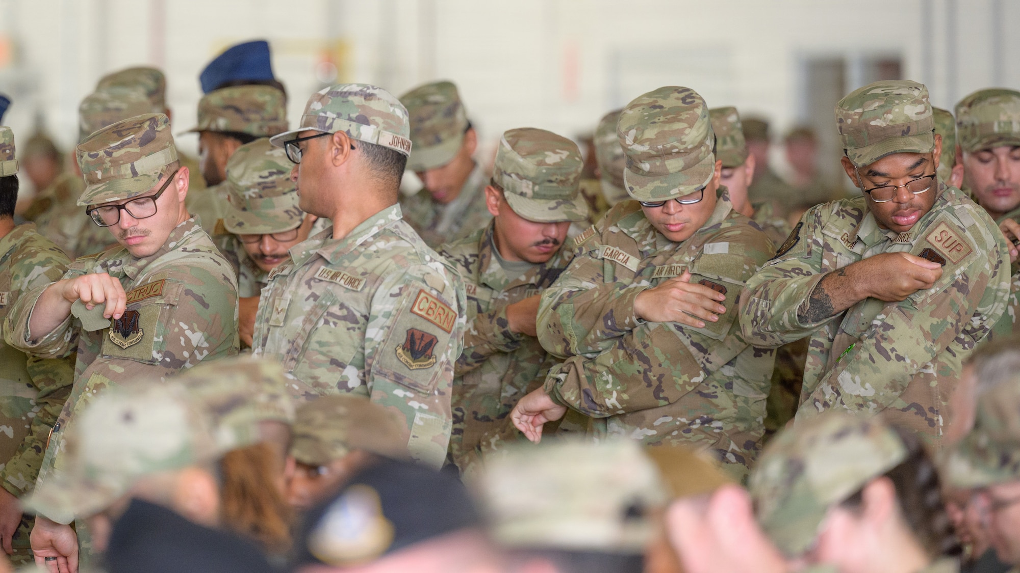 Airmen replace their Air Education and Training Command patches with Air Combat Command during the 49th Wing change of command and reassignment ceremony at Holloman Air Force Base, New Mexico, June 4, 2026. The reassignment to ACC is intended to optimize training pipelines, accelerating production of combat-ready Airmen at the primary F-16 Fighting Falcon and MQ-9 Reaper schoolhouse in the Air Force. (U.S. Air Force photo by Senior Airman Bob Teichmann)