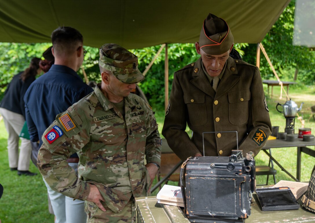 Command Sgt. Maj. Evan Lewandowski, First Army Division East, observes historic camera alongside historic reenactors at Chateau Voilly, the original World War II Headquarters for the U.S. Army Press Camp in Normandy, France.