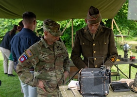 Command Sgt. Maj. Evan Lewandowski, First Army Division East, observes historic camera alongside historic reenactors at Chateau Voilly, the original World War II Headquarters for the U.S. Army Press Camp in Normandy, France.