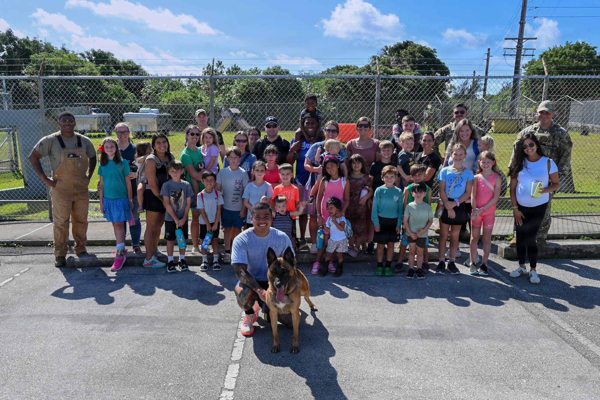 Parents and students from the military home school base tour group pose for a group photo with airmen from the 36th Security Forces Squadron military working dog team.