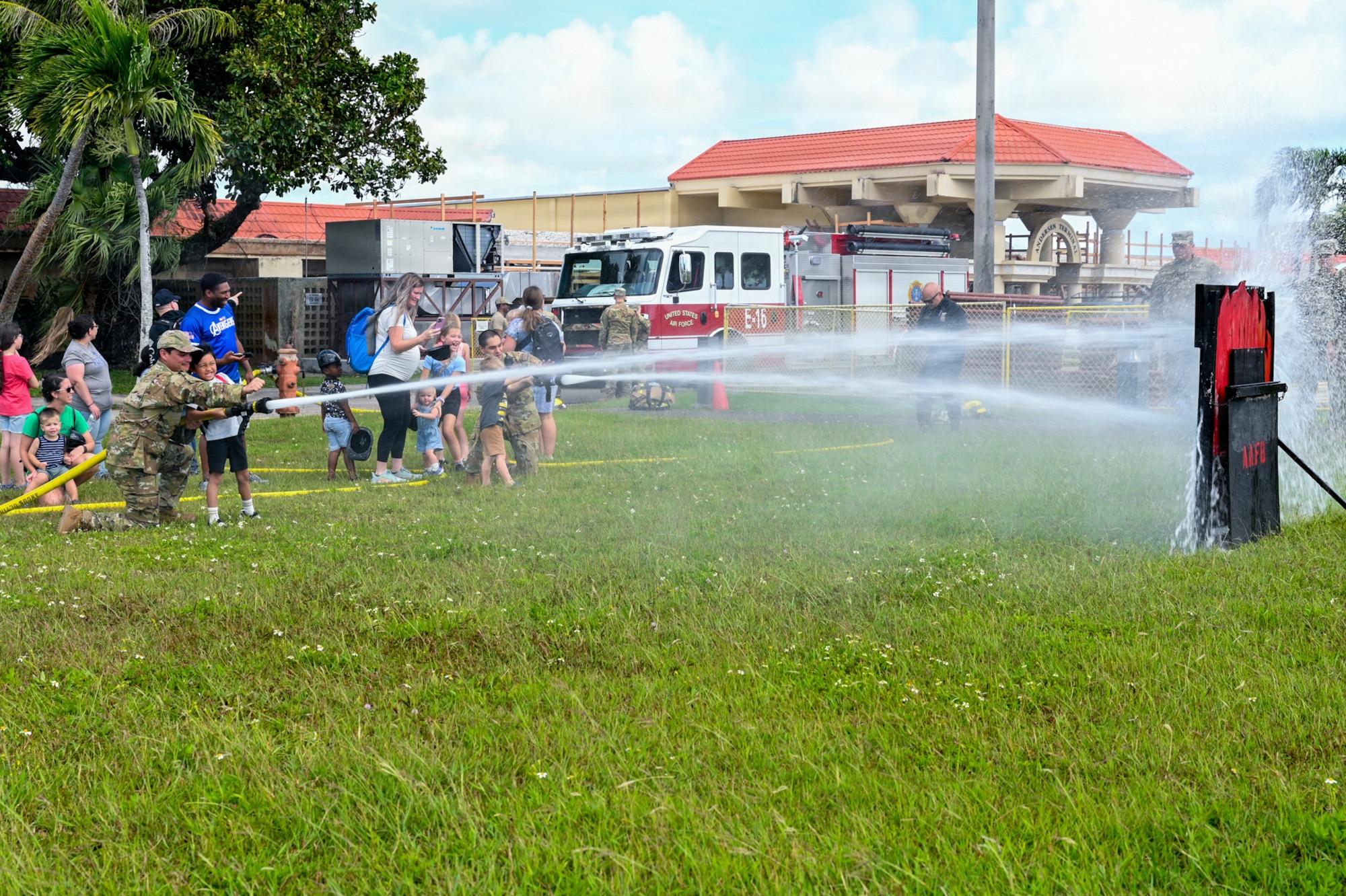 Military home school students take turns putting out a simulated fire with a fire hose.
