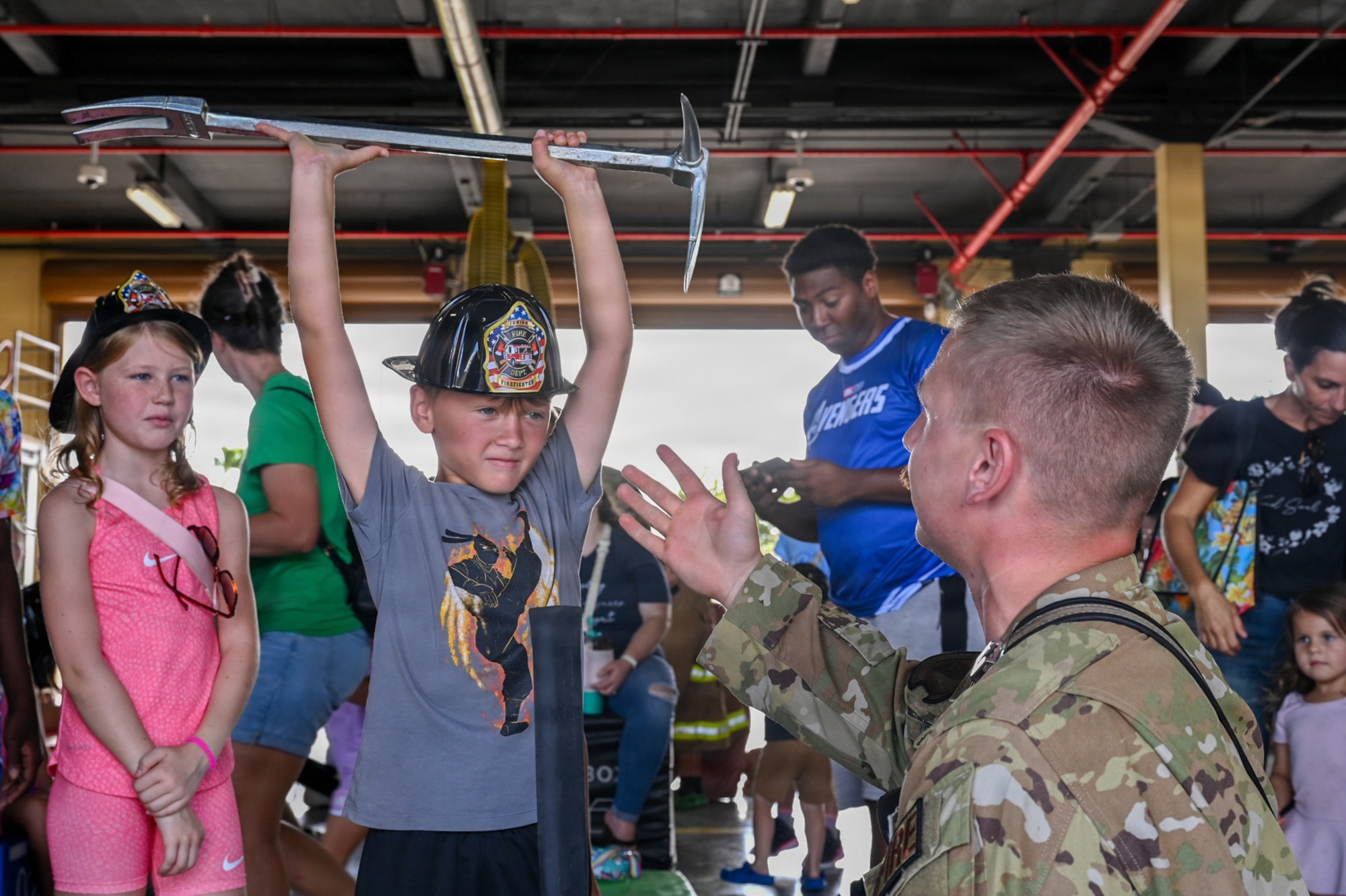 A military home school student, left, lifts a Halligan bar above his head under the supervision of Staff Sgt. Skylor Caruso, right, 36th Civil Engineer Squadron lead firefighter.