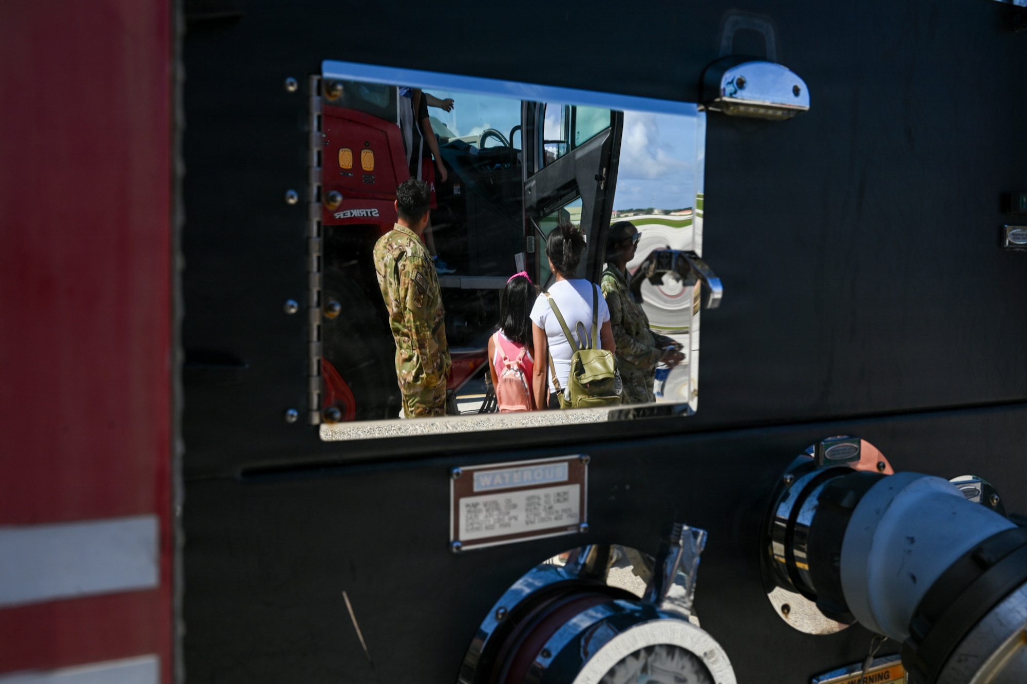 From left, U.S. Air Force SrA Josue Velasquez, 36th Civil Engineer Squadron driver operator, shows a military home school student and parent the interior of a fire truck.