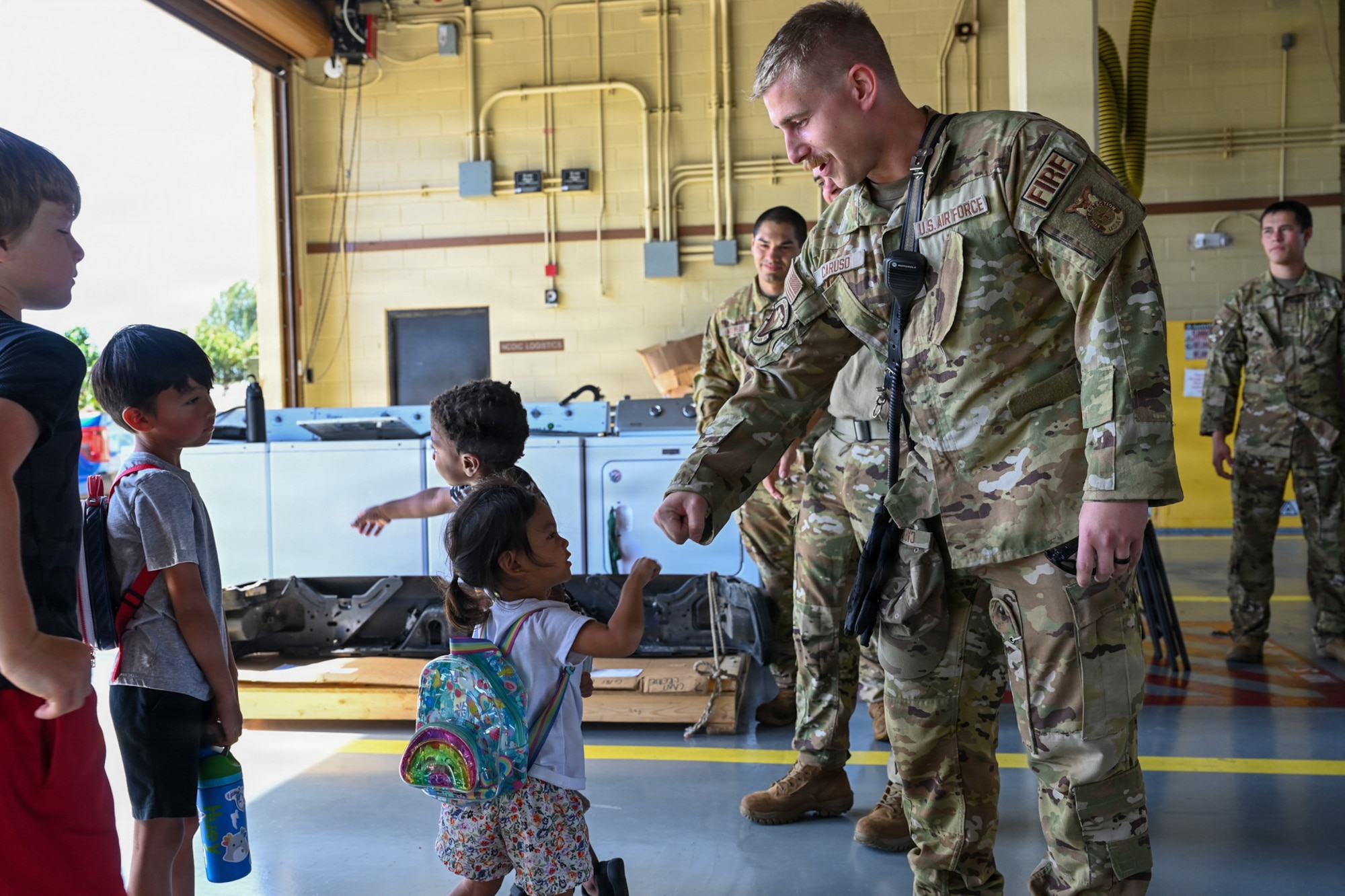 A military home school student, left, shares a greeting with Staff Sgt. Skylor Caruso, right, 36th Civil Engineer Squadron lead firefighter.