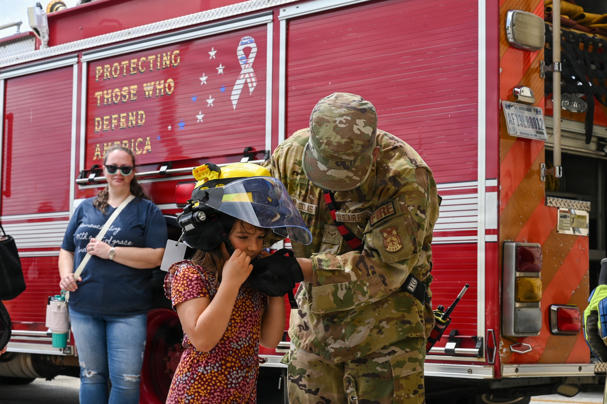 U.S. Air Force Airman 1st Class Brian San Nicolas, right, 36th Civil Engineer Squadron firefighter, assists a military home school student, left, with putting on a protective helmet.