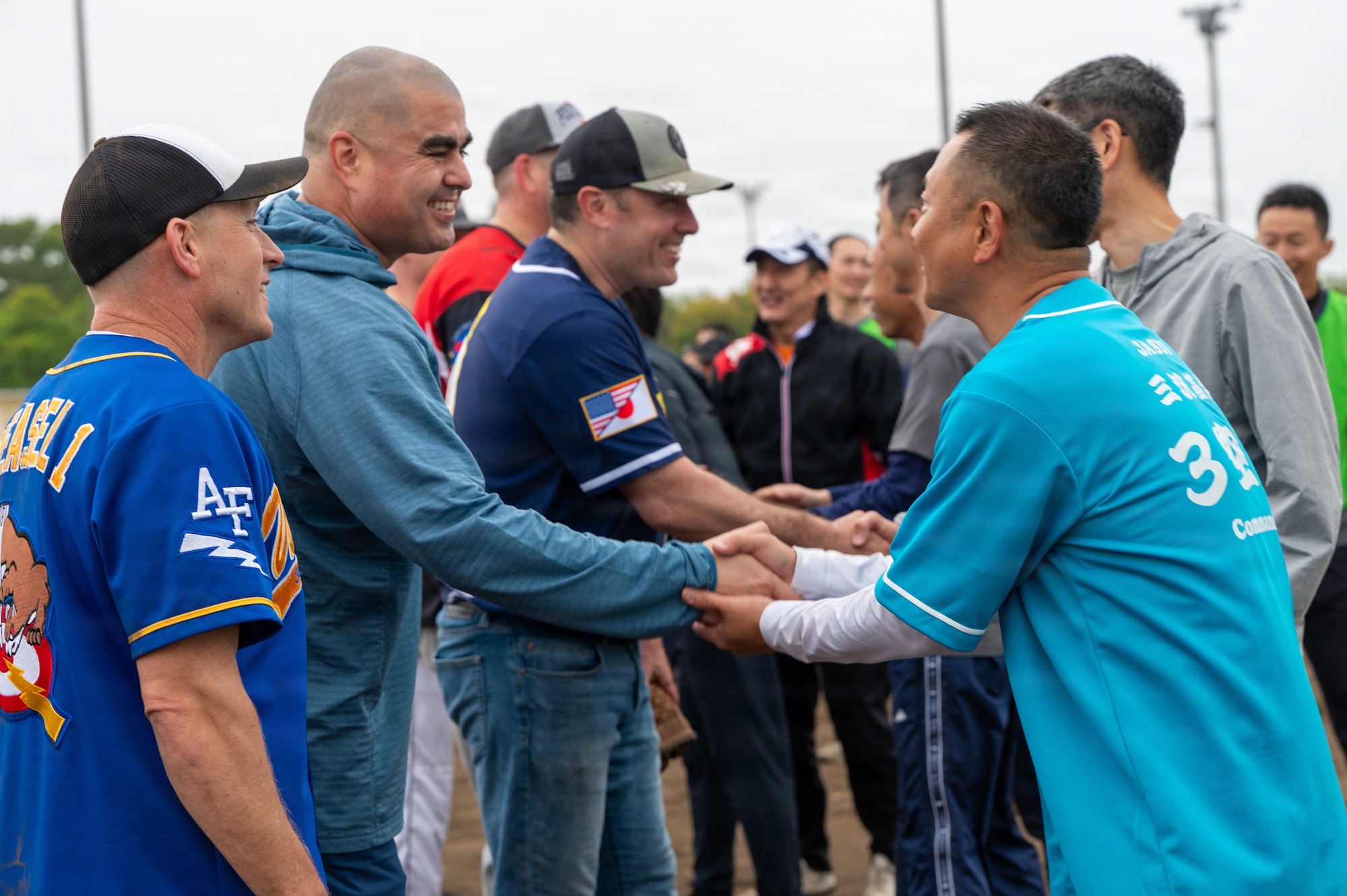 U.S. military and Japan Air Self-Defense Force participants exchange postgame greetings following a softball game during the 2026 Sakura Olympics