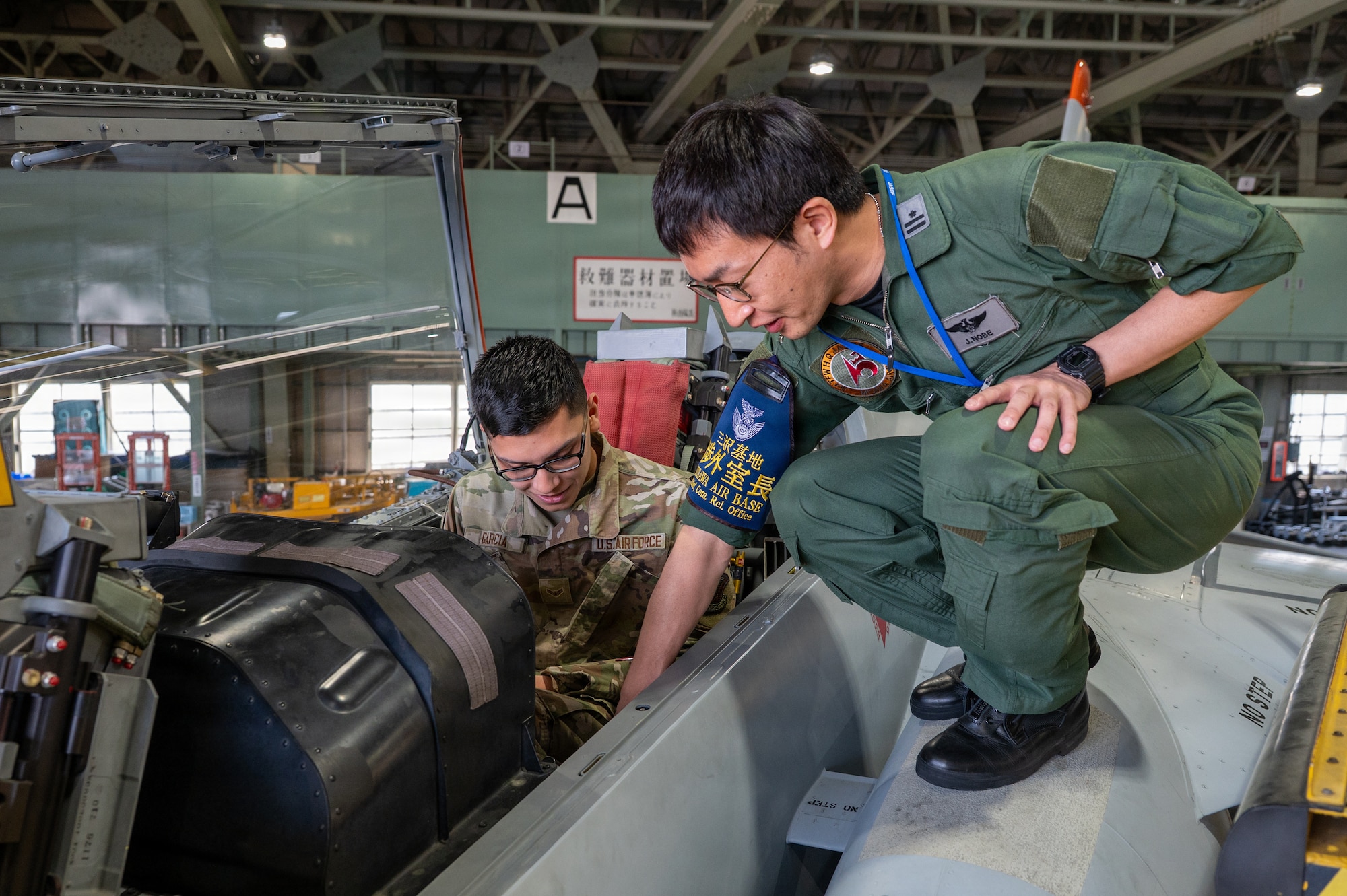 U.S. Air Force Airman 1st Class Andres Garcia, 35th Maintenance Squadron electrical and environmental systems technician, receives a Kawasaki T-4 trainer aircraft familiarization from Japan Air Self-Defense Force Maj. Jungo Nobe, 3rd Air Wing Community Relations Office chief, during a Wild Weasel immersion tour