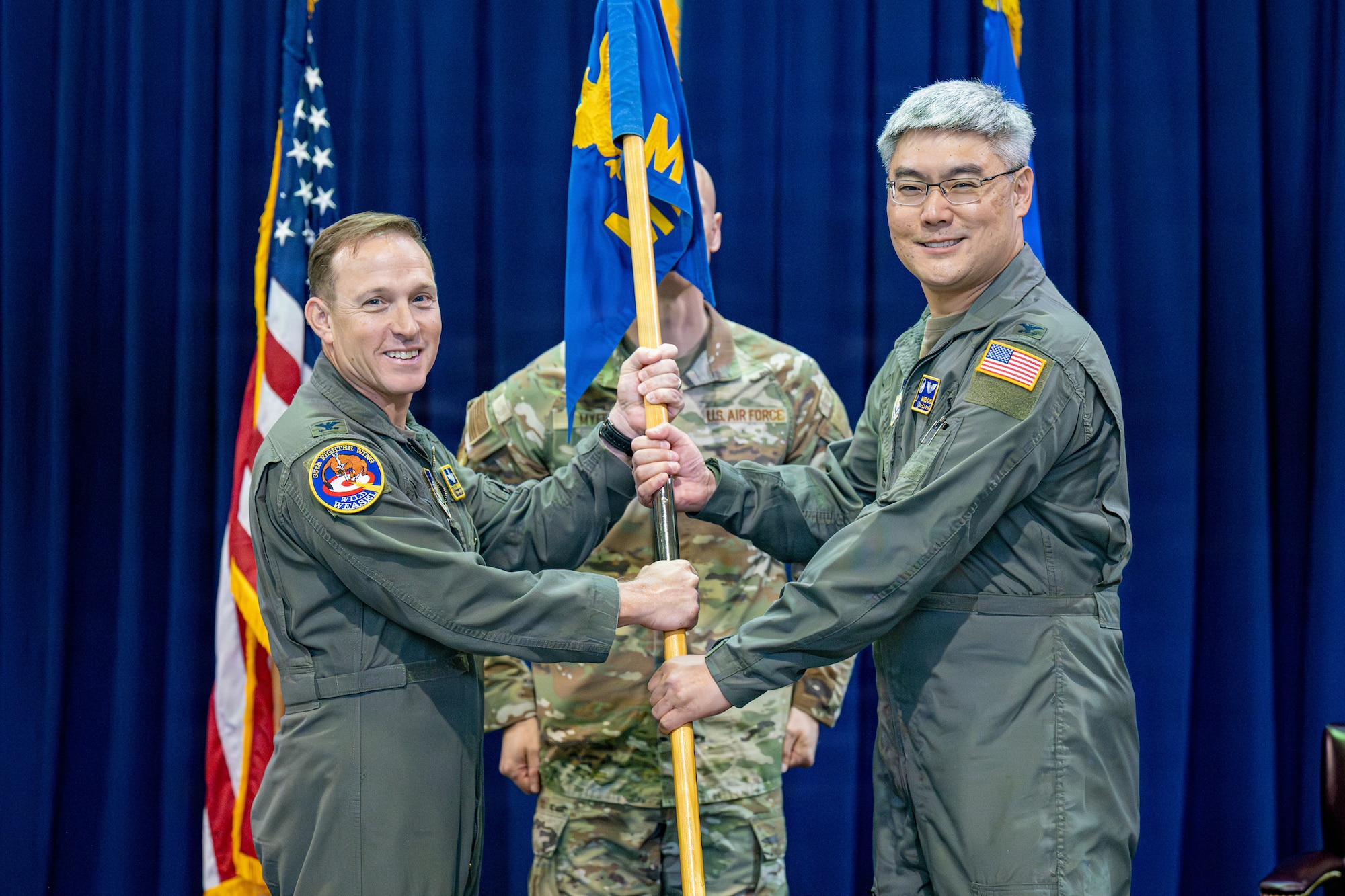 U.S. Air Force Col. Paul Davidson, 35th Fighter Wing commander, passes the 35th Medical Group (MDG) guidon to Col. James Choi, incoming 35th MDG commander, during a change of command ceremony.