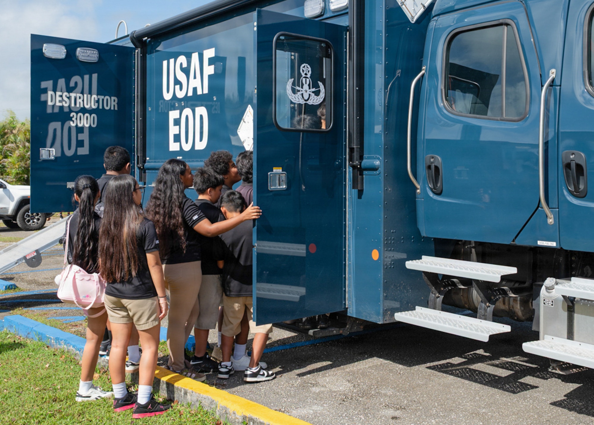 Middle school students climb into an explosive ordnance disposal vehicle during a career day event with Team Andersen's explosive ordnance disposal team.