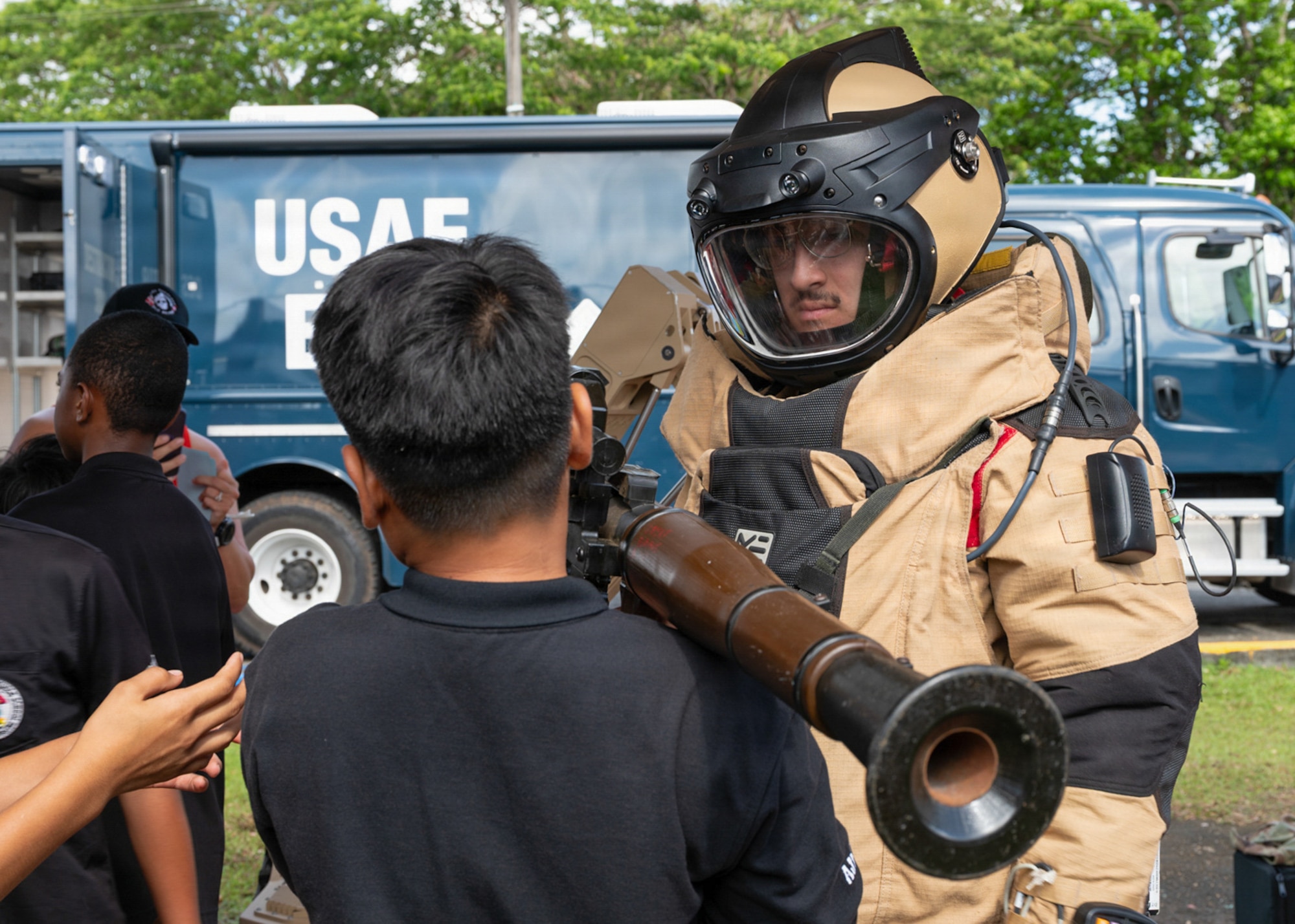 U.S. Air Force Airman 1st Class Stone Kypros, 36th Civil Engineer Squadron explosive ordnance disposal technician, assists a student with handling a deactivated rocket-propelled grenade launcher.