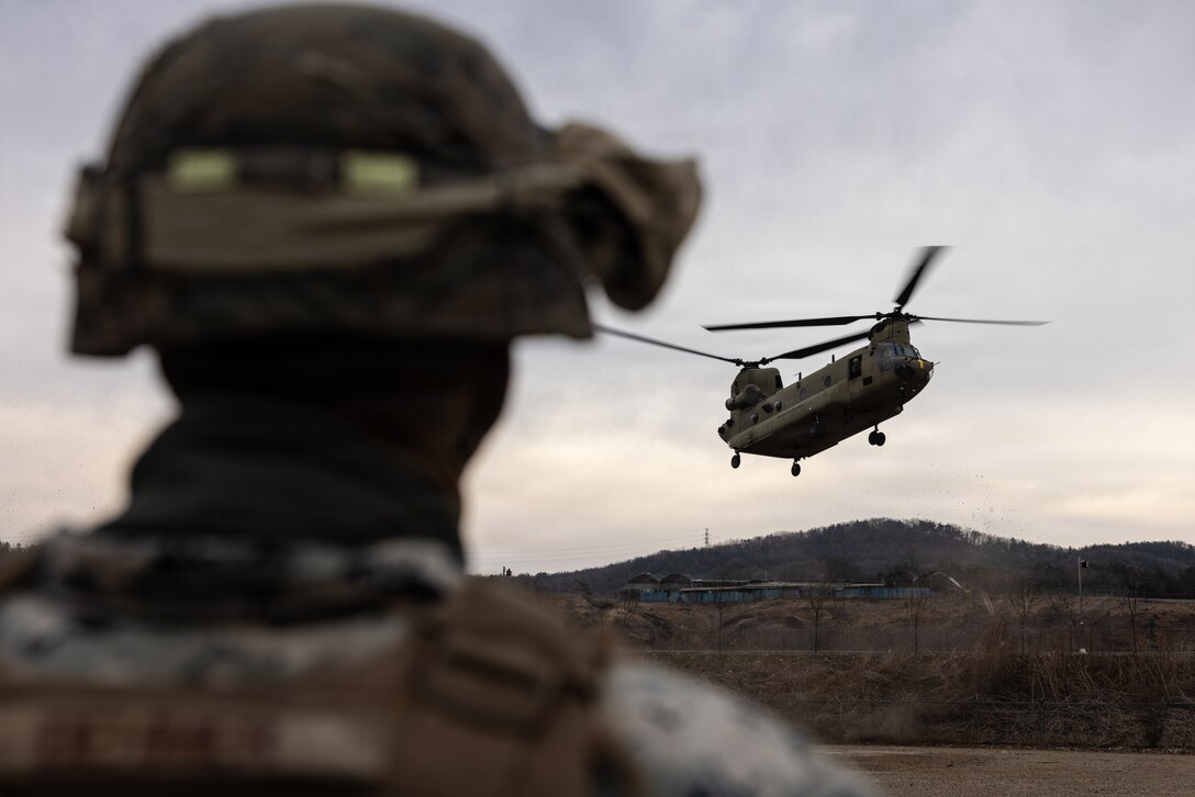 A U.S. Marine Corps Cpl. Nathaniel Dehmer, logistics specialist with 12th Littoral Logistics Battalion, 12th Marine Littoral Regiment, 3rd Marine Division, observes as U.S. Soldiers with 2nd General Support Aviation Battalion, 2nd Combat Aviation Brigade, 2d Infantry Division/ROK-U.S. Combined Division, operate a CH-47 Chinook during a helicopter support team training event at Rodriguez Live-Fire Complex, Republic of Korea, Feb. 26, 2026. The Marines and Soldiers executed day and night HST operations to improve their aerial transportation skills and refine their ability to support distributed operations in multiple environments. Dehmer is a native of Minnesota. (U.S. Marine Corps photo by Lance Cpl. Robert Blanks)