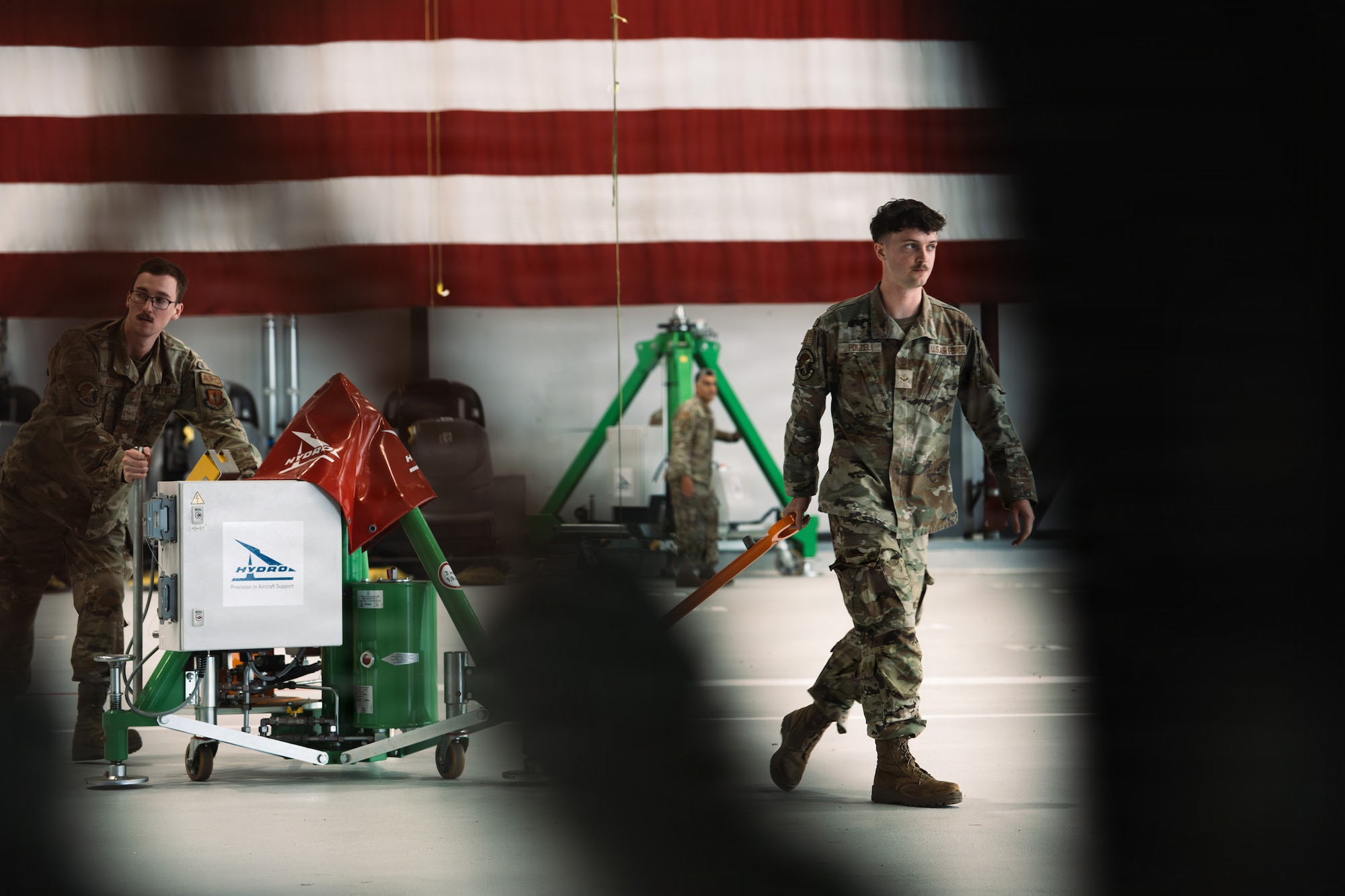 U.S. Air Force Airman 1st Class John Noble, left, and U.S. Air Force Airman 1st Class Zachery Polzel, both 86th Maintenance Squadron aircraft inspections journeymen, pull a hydro electronic jacking and leveling control system towards a C-130J Super Hercules to aid with repairs at Ramstein Air Base, Germany, June 2, 2026.