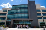 A group of people stand outside in front of a large building posing for a group photo.