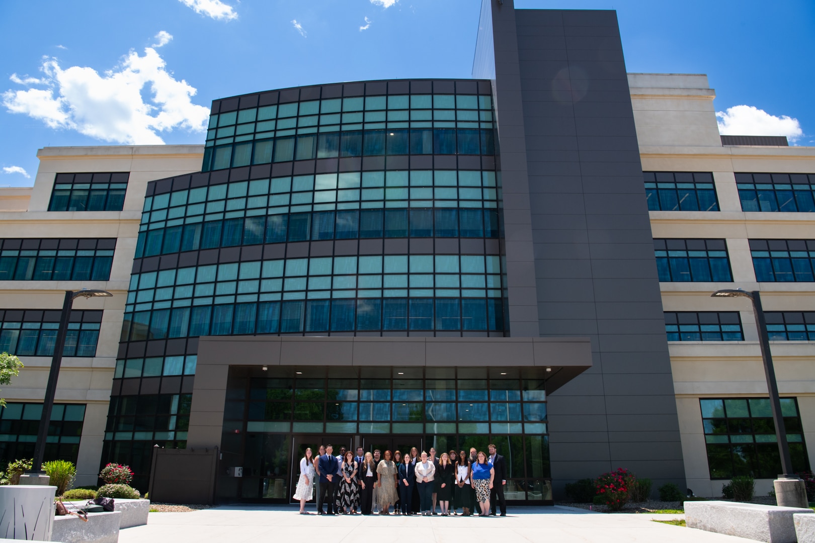 A group of people stand outside in front of a large building posing for a group photo.