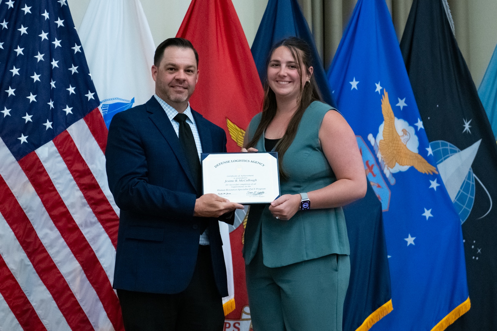 People stand indoors on a stage holding a certificate.