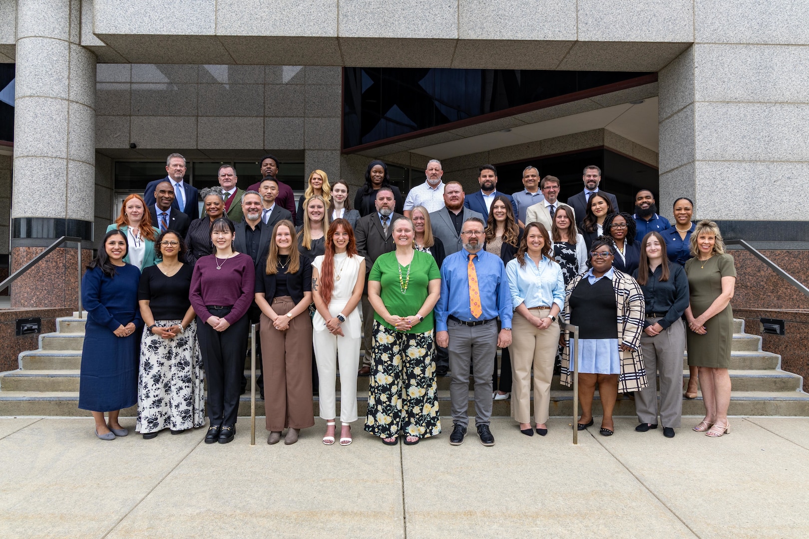 A group of people stand outside in front of a building posing for a group photo.