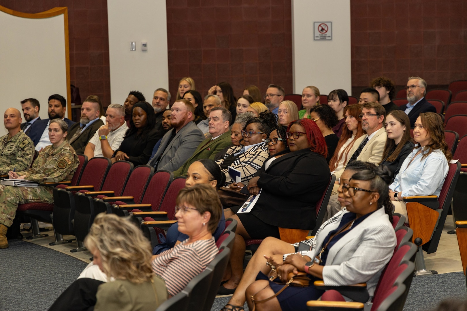 A group of people sit inside an auditorium.