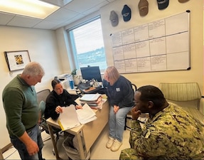 Lt. Brittney Grossman, the Radiation Health Officer assigned to Navy Medicine Readiness and Training Unit Portsmouth, NH, reviews a shipyard worker medical record with the clinics Radiation Health Department personnel, Hospital Corpsman Second Class Qasim Cummingham and Physical Science Technicians, Patti-Anne Hanson and Paul Vasaturo, onboard NMRTC Portsmouth NH, in Kittery, Maine, April 24 ,2026. Navy Radiation Health programs are audited annually by the Bureau of Medicine and Surgery to ensure regulatory compliance and high reliability.  NMRTU Portsmouth was recognized as having a top-tier program during their April 2026 audit. NMRTU Portsmouth is a branch clinic of Navy Medicine Readiness and Training Command, New England. NMRTC is the comprehensive health care system for the U.S. Navy in the Northeast region, providing medical care to 70,000 eligible beneficiaries. (U.S. Navy photo by Cmdr. Jenny Paul)