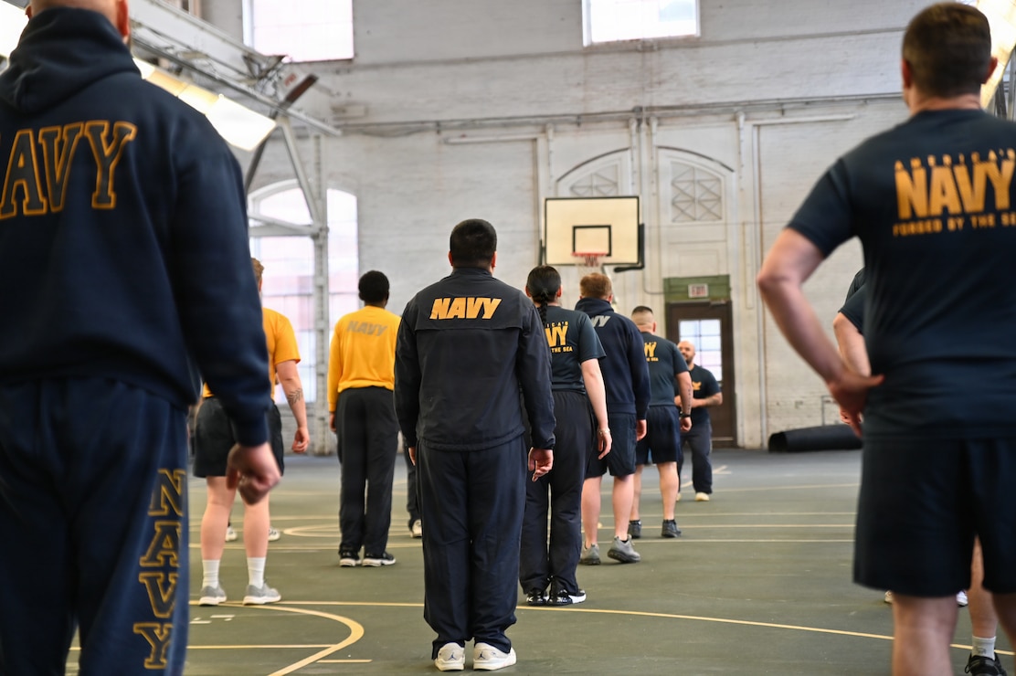 U.S. Sailors with Naval Support Activity Washington (NSAW) stand in formation before beginning a warm-up routine at the Washington Navy Yard, Washington, D.C.