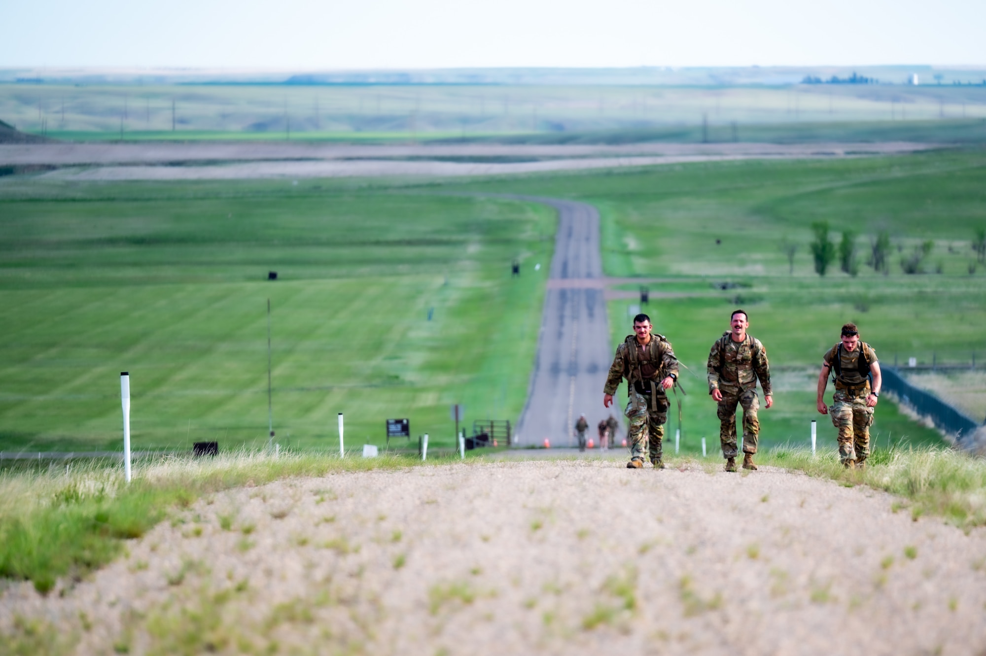 Three participants in a Norwegian Foot March hike up a hill at Malmstrom Air Force Base, Montana, May 26, 2026.