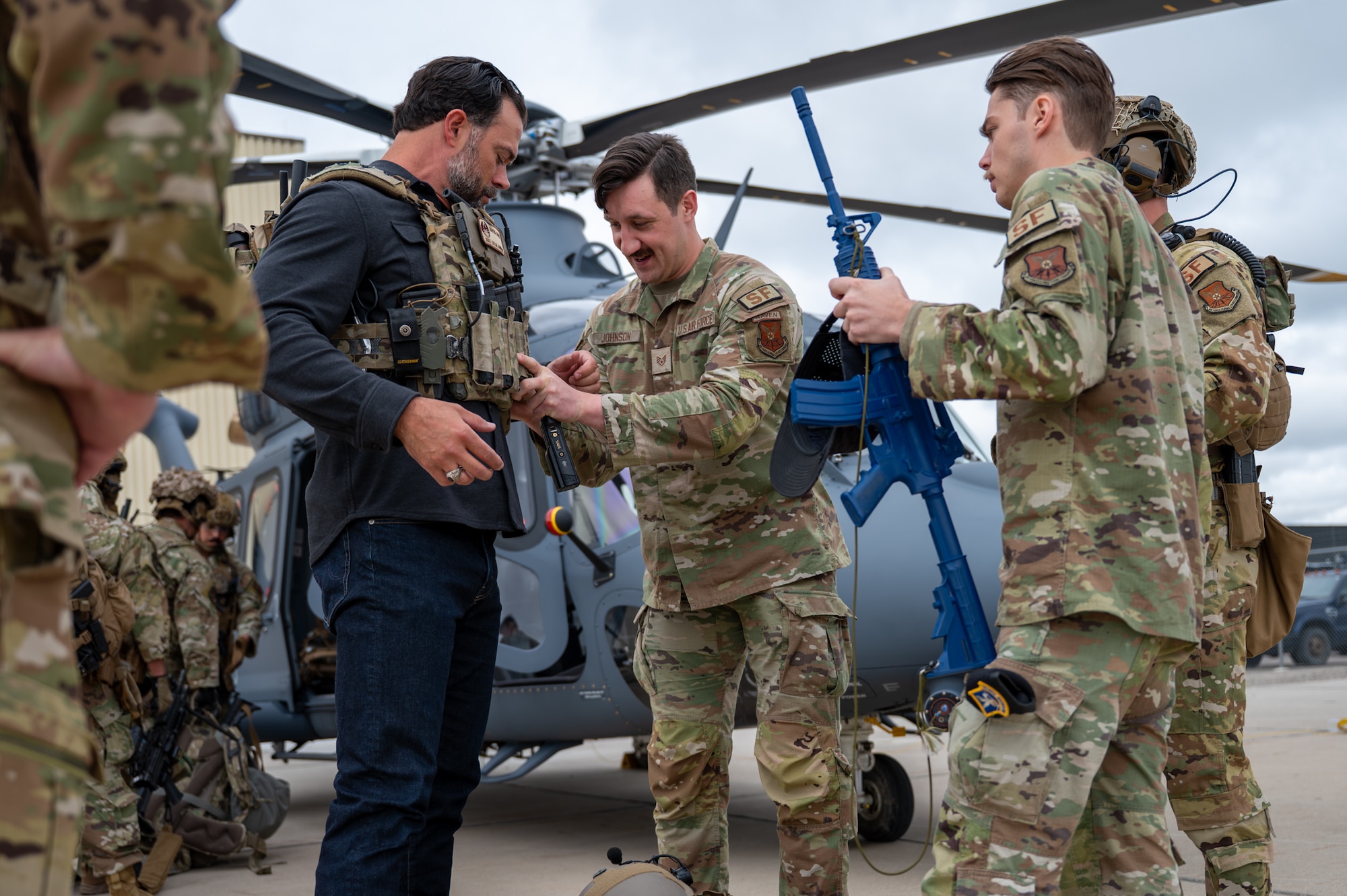 Military personnel assist the Under Secretary of the Air Force as he puts on tactical gear.