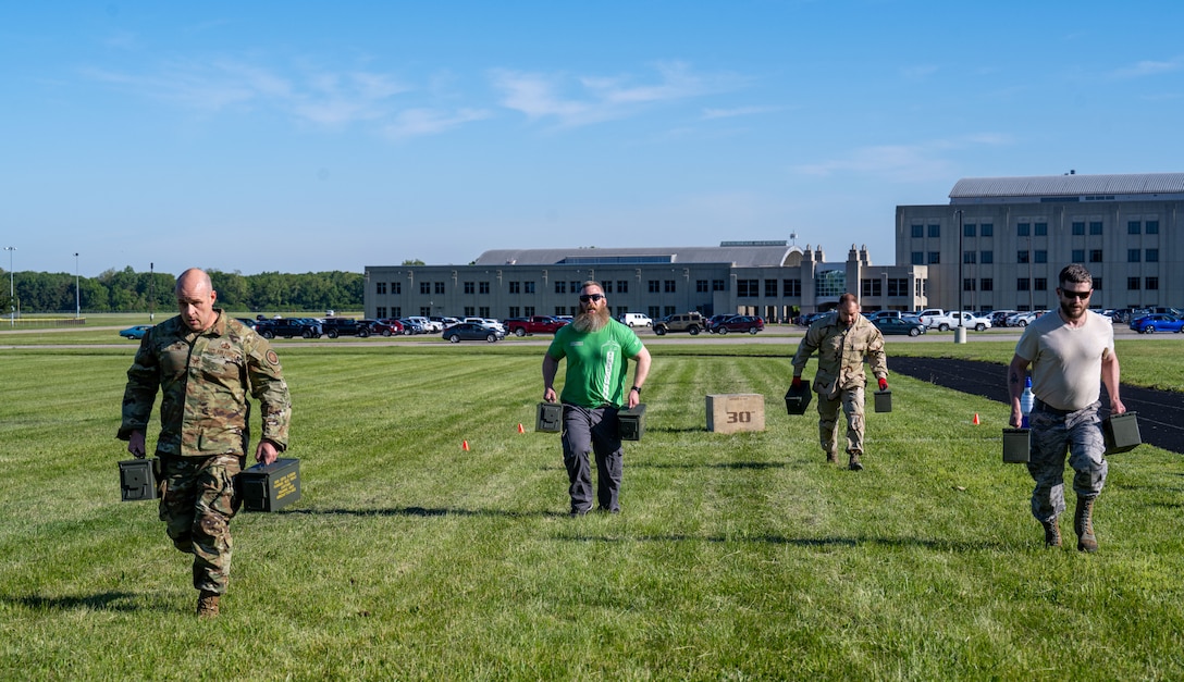 Men wearing military and civilian attire compete in an obstacle course
