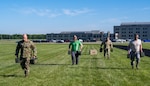 Men wearing military and civilian attire compete in an obstacle course