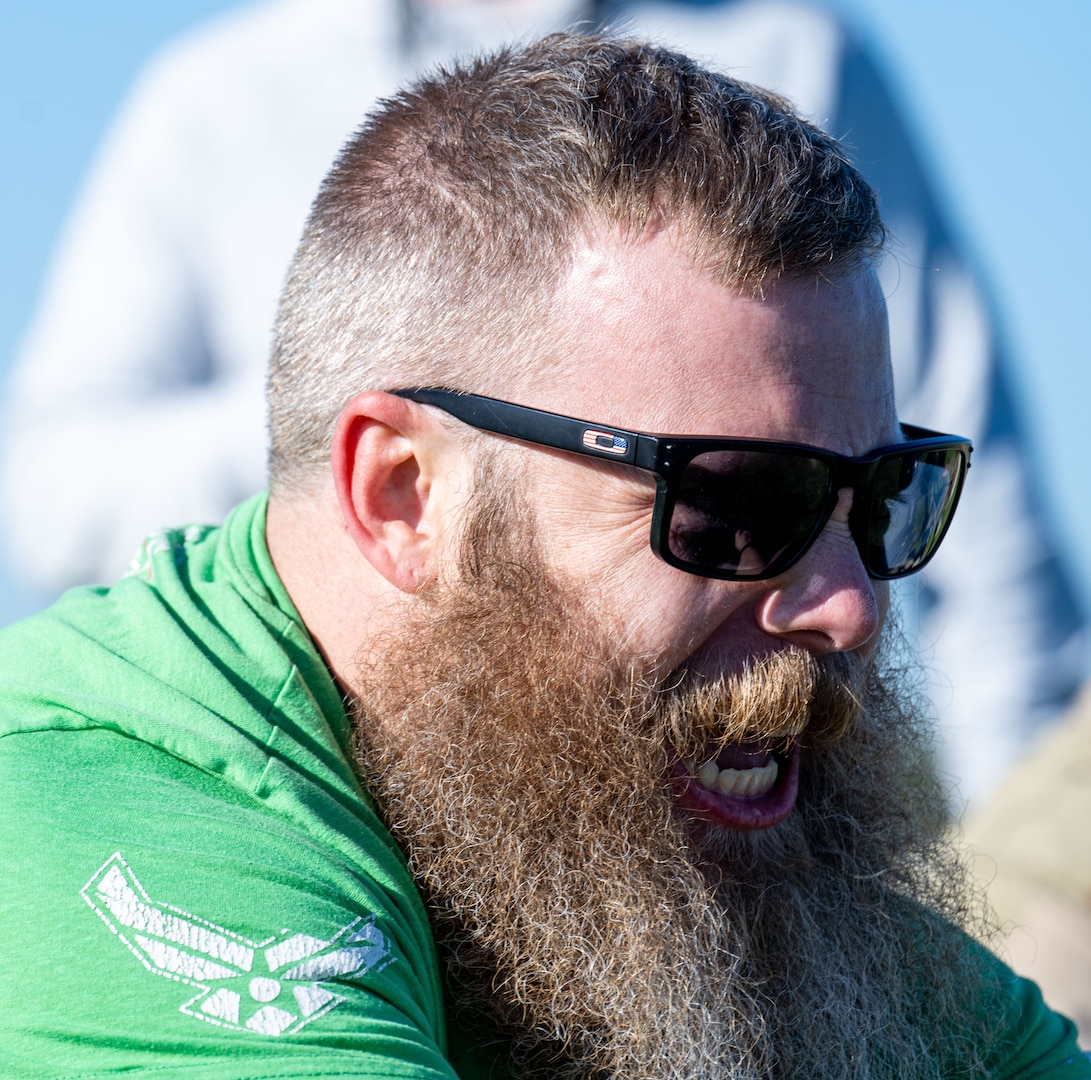 A man wearing a green shirt and black sunglasses participates in an obstacle course