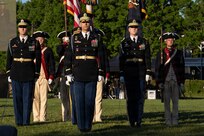 Army Soldiers in both modern ceremonial uniforms and Revolutionary War-era uniforms are standing in formation during an outdoor show.