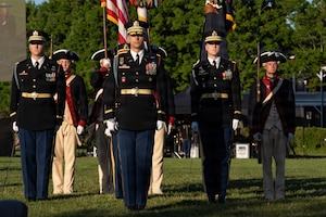 Army Soldiers in both modern ceremonial uniforms and Revolutionary War-era uniforms are standing in formation during an outdoor show.