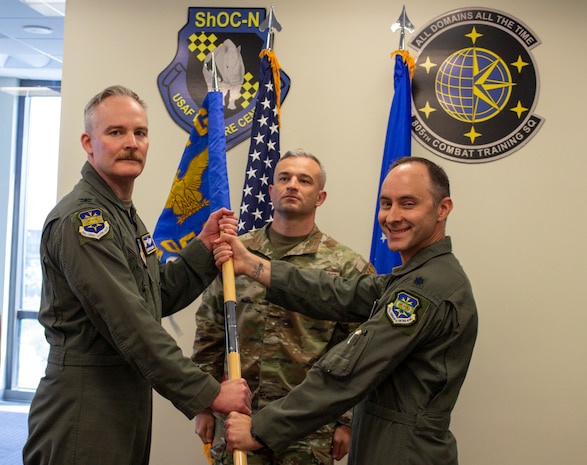 two US Airmen hold a unit guidon flag in between them