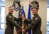 two US Airmen hold a unit guidon flag in between them