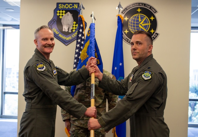 two US Airmen hold a unit guidon flag in between them