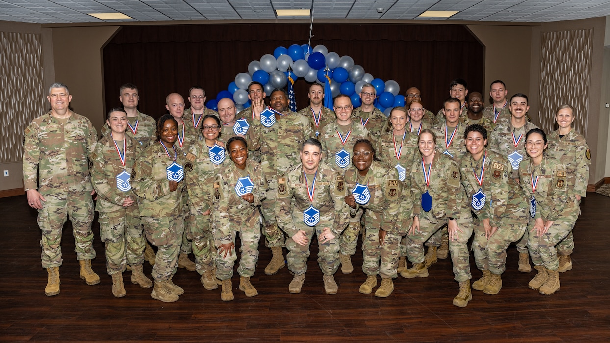 A group photo of men and women, wearing military camouflage uniforms, most wearing blue and white MSgt lanyards
