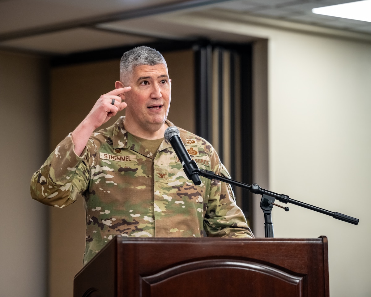 A man, wearing military camouflage uniform, gestures while speaking behind a podium and microphone