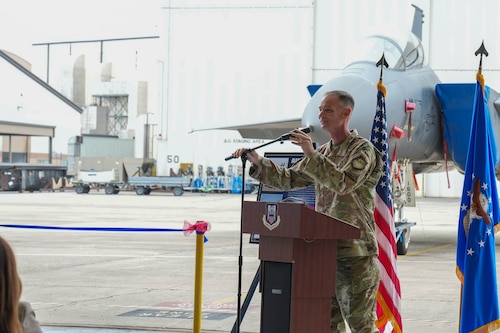 an airman holds the microphone while standing behind a podium.