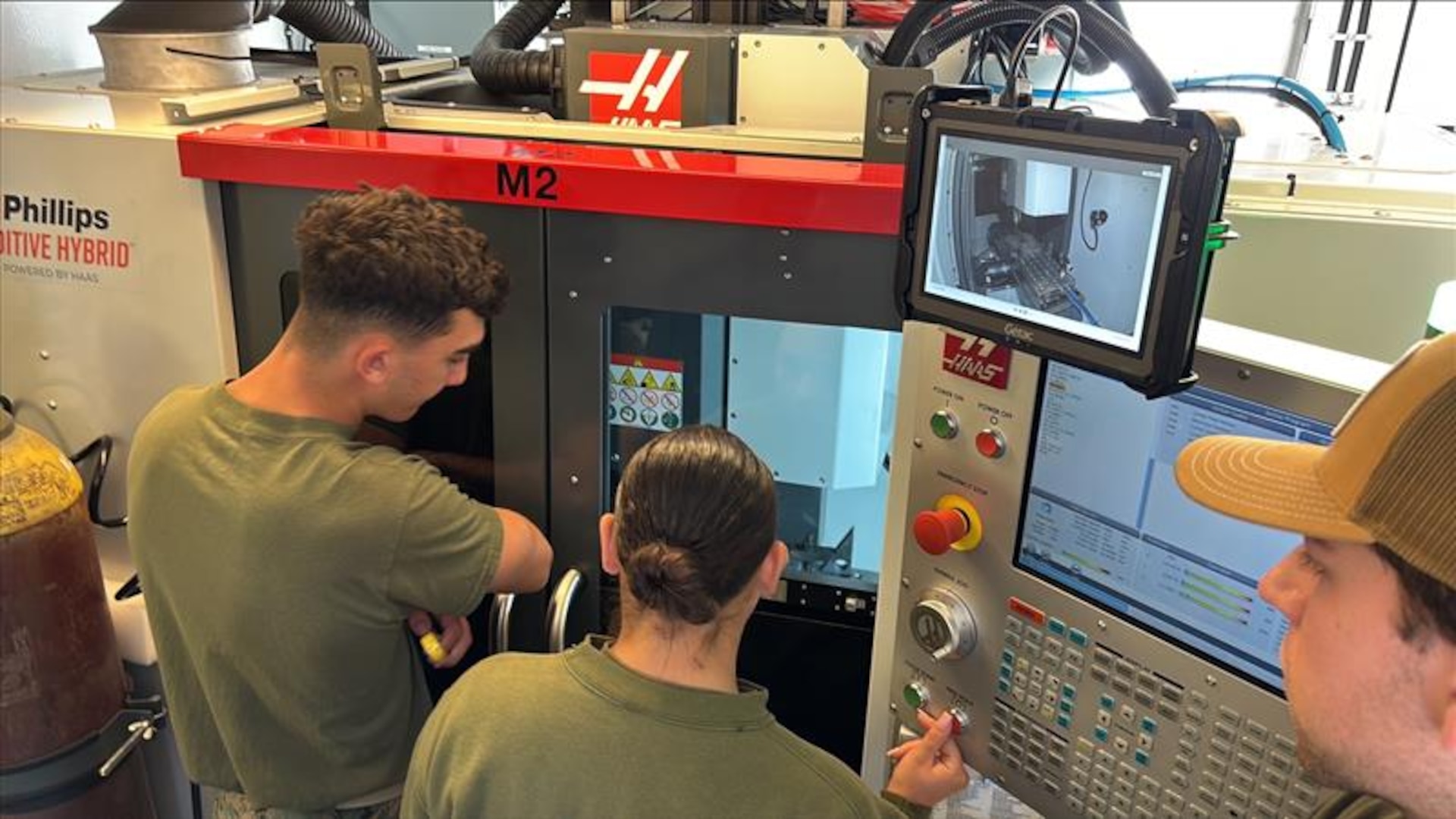 (CAMP PENDLETON, Calif.) – Marines assigned to 1st Maintenance Battalion observe a machining operation on the Advanced Integrated Mobile Machine Shop (AIMMS) hHybrid sSystem alongside Naval Surface Warfare Center, Carderock Division engineer Ryan Smith during New Equipment Training (NET) at Camp Pendleton, California. The hybrid system combines additive and subtractive manufacturing capabilities, enabling Marines to fabricate and repair metal components in operational environments rather than relying solely on traditional supply chains.