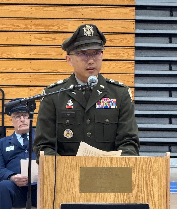 A man wearing an Army green uniform stand behind a podium