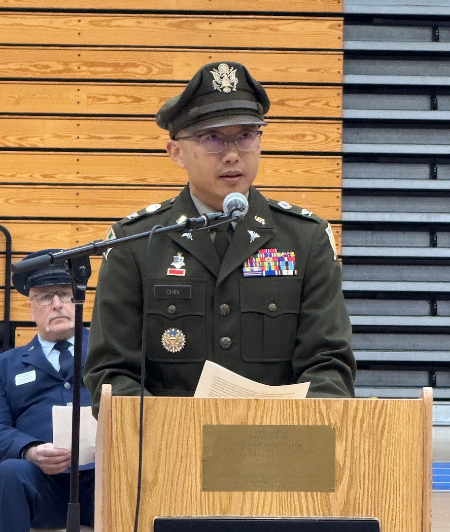 A man wearing an Army green uniform stand behind a podium
