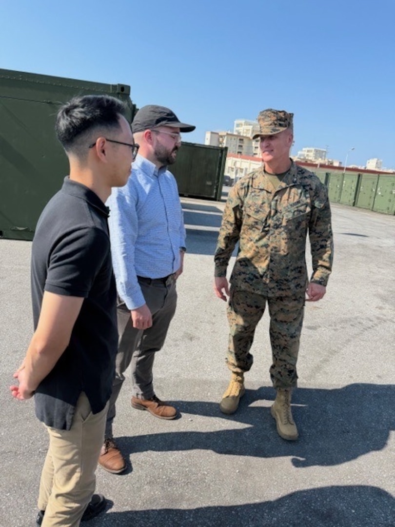 (OKINAWA, Japan) – Naval Surface Warfare Center, Carderock Division engineers Brennen Cheung and Ryan Fisher speak with Brig. Gen. Collins, commanding general of the 3rd Marine Logistics Group, about New Equipment Training (NET) supporting the recently fielded Advanced Integrated Mobile Machine Shop (AIMMS) in Okinawa, Japan. AIMMS provides Marines with a deployable manufacturing capability designed to support forward-deployed maintenance and repair operations closer to the point of need.