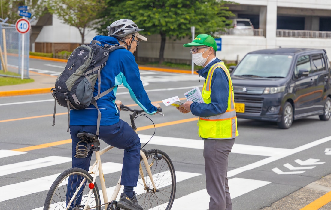 Commander, Fleet Activities Yokosuka Safety Department representative speaks with a bicyclist about traveling in the correct direction of traffic and using designated bike lanes during a traffic safety engagement at Commander, Fleet Activities Yokosuka on April 22, 2026. The campaign reinforces safe and predictable movement for all roadway users. CFAY remains committed to enhancing safety and awareness across the installation.